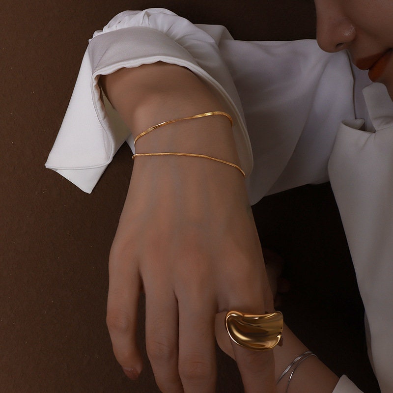gold and titanium snake chain bracelet options flat lay