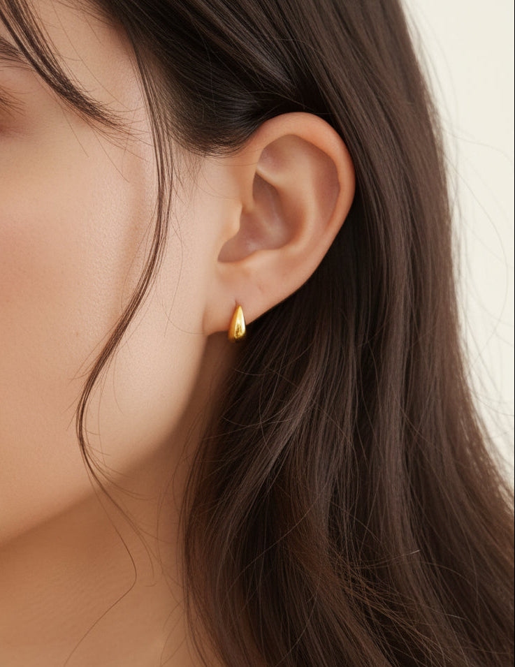 gold teardrop stud earrings worn on model ear close up