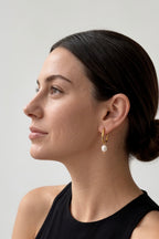 gold oval huggie hoop earrings worn on model ear waterproof