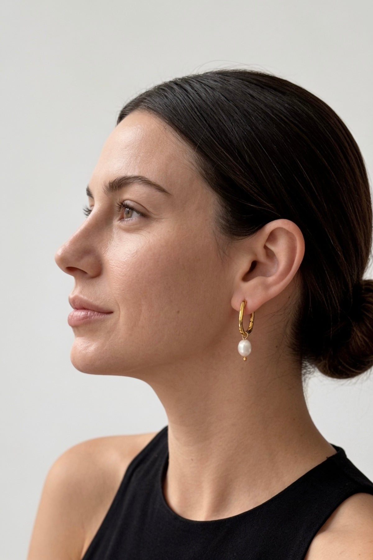 gold oval huggie hoop earrings worn on model ear waterproof